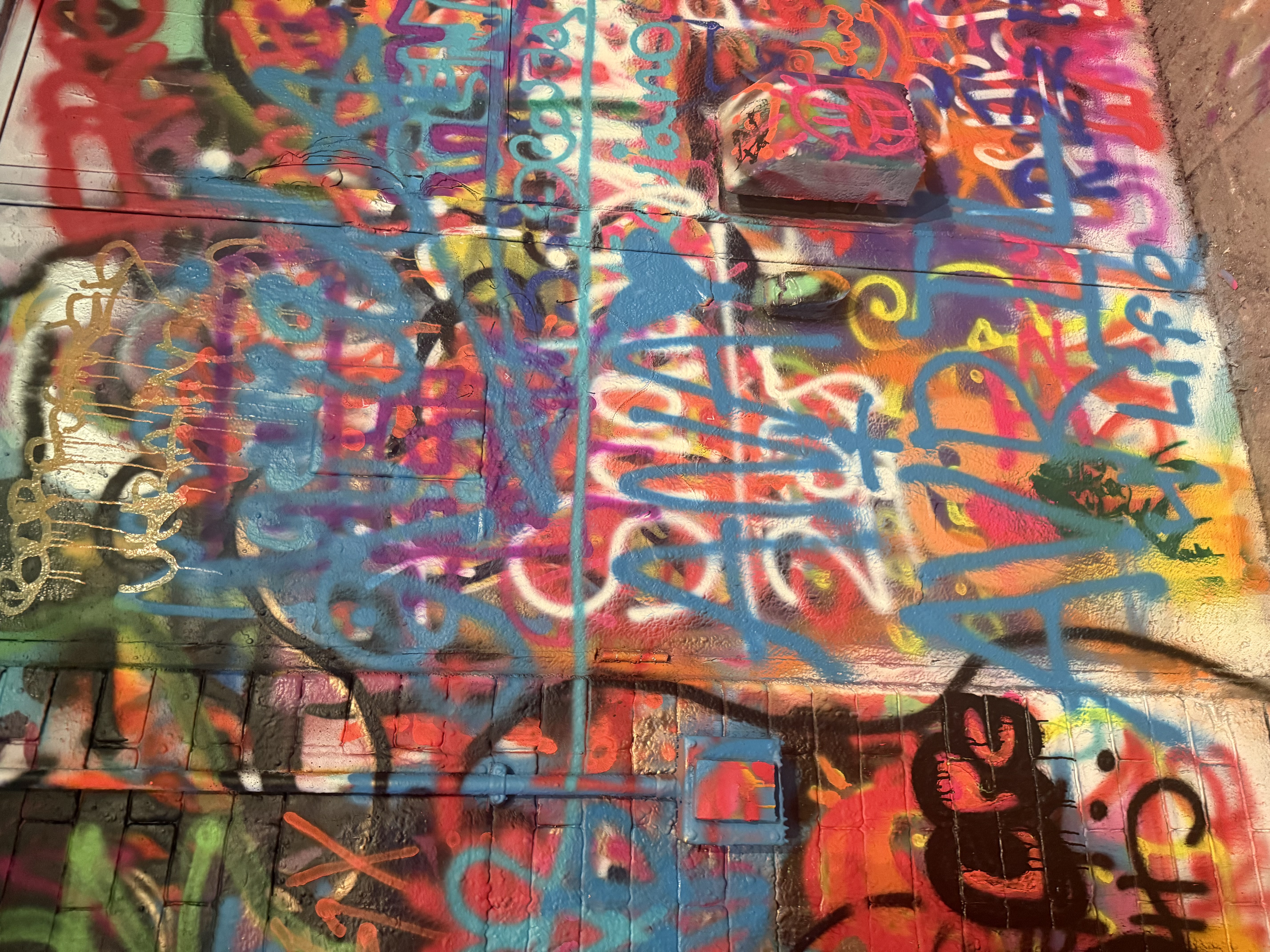 Colorful layered graffiti covering a brick wall